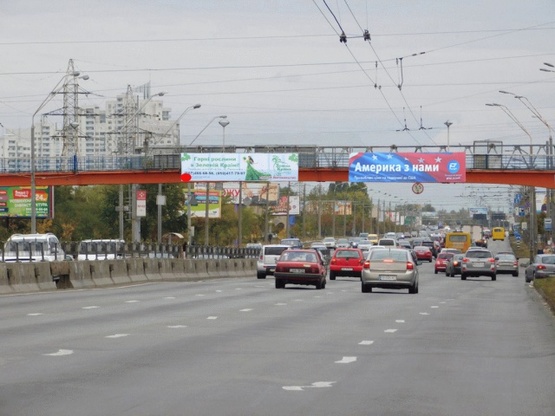 Фото рекламної площини за адресою Бандеры Степана пр-т./ Иорданская ул. надземный пешеходный переход, из центра